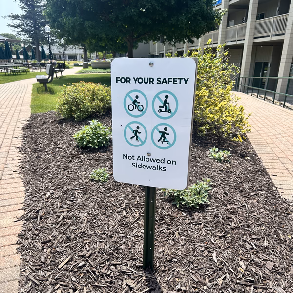 Outdoor safety sign with symbols of no bikes, skateboards, scooters or running.